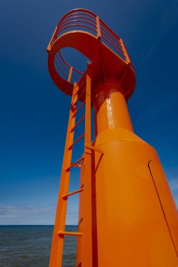 Küçük modern kırmızı deniz feneri direği yenilenmiş beton köstebek mavi gökyüzünde izole.