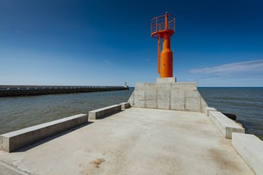 Küçük modern kırmızı deniz feneri direği yenilenmiş beton köstebek mavi gökyüzünde izole.