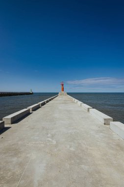 Küçük modern kırmızı deniz feneri direği yenilenmiş beton köstebek mavi gökyüzünde izole.