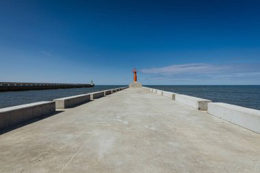 Küçük modern kırmızı deniz feneri direği yenilenmiş beton köstebek mavi gökyüzünde izole.