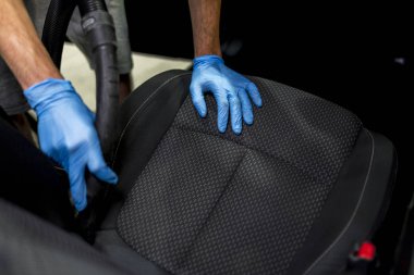 Arabanın salonunu süpüren bir adam. 