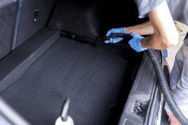 Arabanın salonunu süpüren bir adam. 