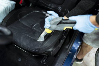 Arabanın salonunu süpüren bir adam. 