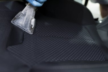 Arabanın salonunu süpüren bir adam. 