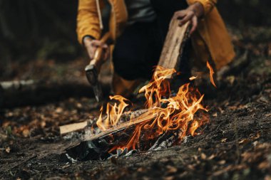 Kamp ateşinin yakın görüntüsü, soğuk bir sonbahar akşamında karanlık orman arka planı.