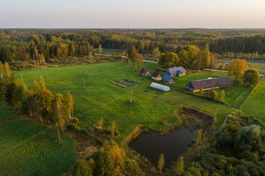 Ormanın ve kırsal alandaki çiftliğin üzerinde yumuşak renkli günbatımı ışığı.