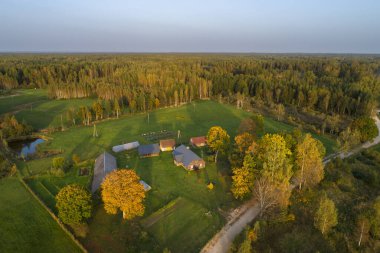 Ormanın ve kırsal alandaki çiftliğin üzerinde yumuşak renkli günbatımı ışığı.