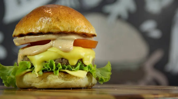 Kotitekoinen juustohampurilainen salaatilla ja kastikkeella puulaudalla — kuvapankkivalokuva