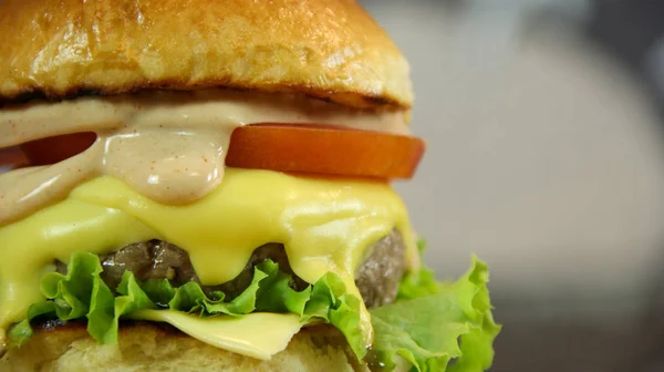 Duży soczysty cheeseburger z Sałatka i sos zbliżenie — Zdjęcie stockowe