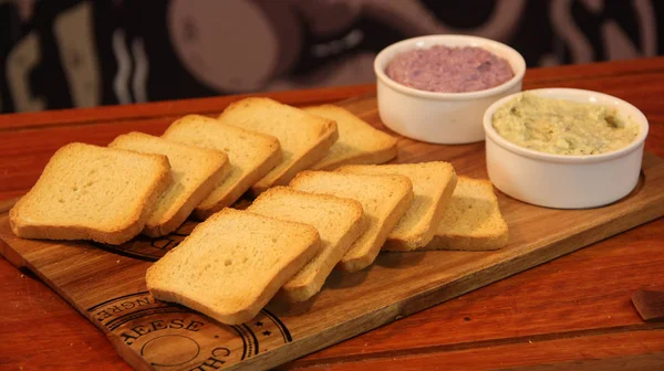 Tost kraker sos kaseleri ile ahşap bir tahta içinde servis