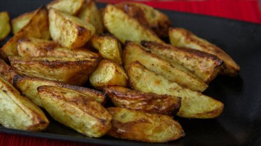 Siyah tepside servis edilen terbiyeli rustik patates kızartması