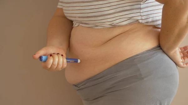 Надмірна вага жінки, що застосовує ін'єкції ліків від діабету в її живіт Ліцензійні Стокові Фото