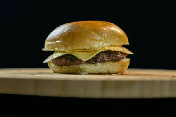 Ahşap tahta siyah arka plan üzerinde basit cheeseburger