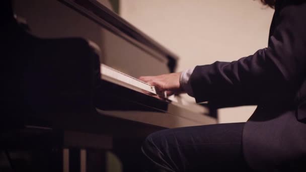 男性のピアニストは スライダーの動きでフィールドの低光と浅い深さのピアノで曲を演奏 — ストック動画