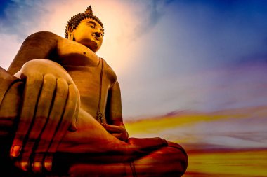 The large golden lord of Buddha statue that is faithful on a beautiful and colourful sky with orange, yellow, red, blue. clipart