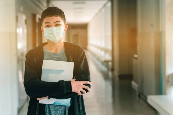 2019 Coronavirus hastalığının ortasında maskeyi takan Asyalı bir erkek lise öğrencisi (COVID-19) salgını ve 2,5..