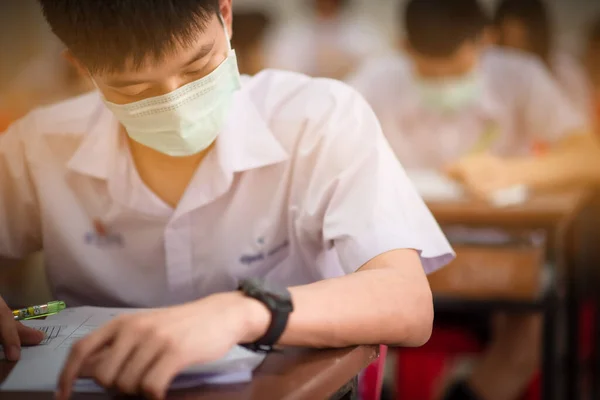 2019 Coronavirus hastalığı (COVID-19) salgını ve 2,5. Başbakan 'ın ortasında final sınavları için maske takan bir Asyalı lise öğrencisi.