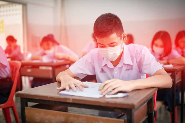 2019 Coronavirus hastalığının tam ortasında (COVID-19) final sınavları için maskeli Asyalı lise öğrencileri maskeleri takıyor..
