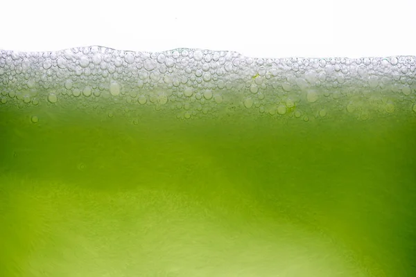 Limon suyu ya da yeşil meyve suyuyla karıştırılmış yakın plan soda köpüklerinin arka planı.