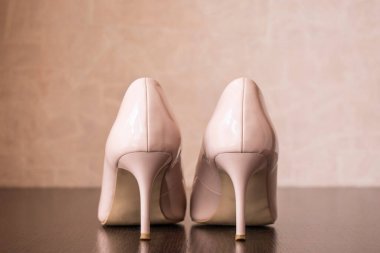 Kahverengi bir rafta duran yüksek topuklu bej ayakkabılar.