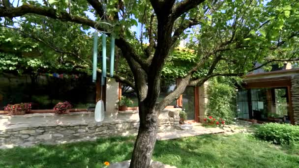 Windglocke hängt am Baum in einem schönen Hausgarten — Stockvideo