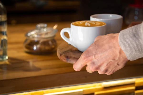 Nahaufnahme einer männlichen Hand, die eine Tasse heißen Kaffee nimmt — Stockfoto