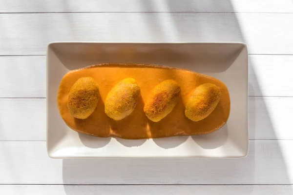 Croquetes de carne frita com molho de creme vegetal em prato branco na cozinha ensolarada. Vista superior em fundo de madeira branco . — Fotografia de Stock