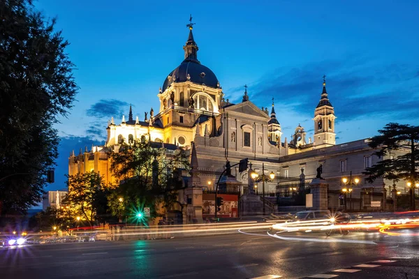 Catedral de Santa María Real de La Almudena en el centro de Madrid por la noche. Vista desde el cruce con luces de coche — Foto de Stock