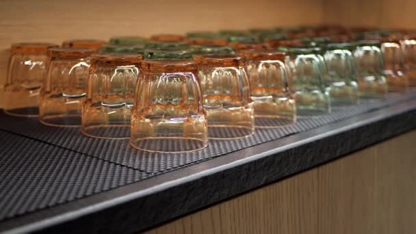 Průhledné sklenice na vodu nebo džus. Sklenice na pití různých barev v dřevěné kuchyňské skříni.
