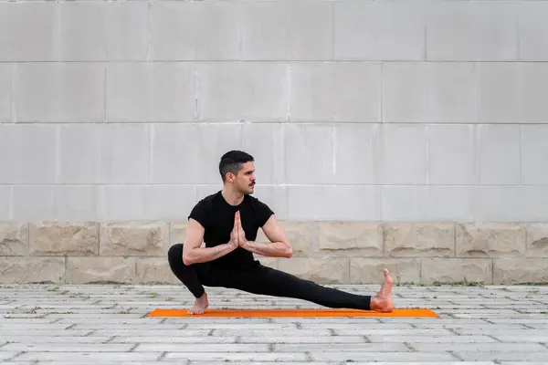 Rovnováha a strečové cvičení venku. Latinský muž cvičit jógu asanas ve městě. — Stock fotografie