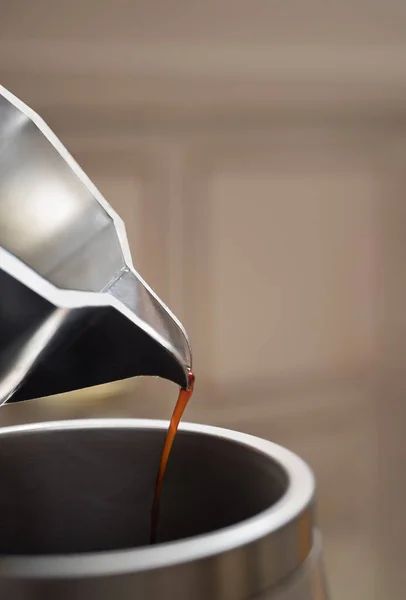 Nahaufnahme des Ausgießens von Kaffee aus einer Mokka-Kanne in einer großen Metall-Thermoskanne. Morgen mit Espresso. — Stockfoto