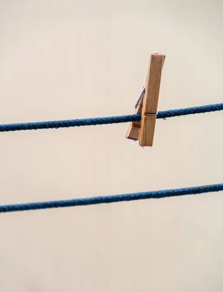Jeden dřevěný kolík na modrém laně s kapkami po dešti na rozmazaném pozadí. — Stock fotografie