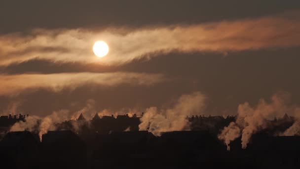 Pôr-do-sol de inverno numa aldeia. A fumaça nasce de chaminés em telhados de casas à luz do sol — Vídeo de Stock