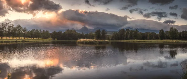 Strba Pond lit by Golden Light at Sunset with High Tatras Mountains in Background, Slovakia.