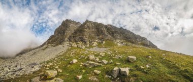 Ön planda kayalar ile bulutlu dağlar