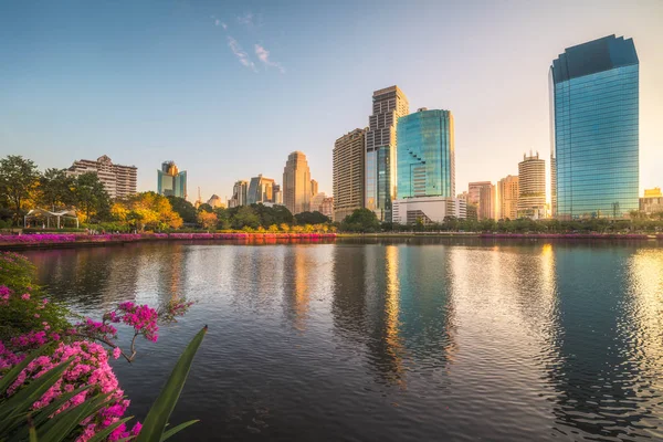 Lake with Purple Flowers in City Park under Skyscrapers at Sunri — Stock Photo, Image
