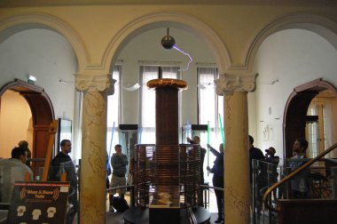 Ziyaretçiler, Sırbistan 'ın başkenti Belgrad' daki Nikola Tesla müzesindeki Yüksek Frekanslı Oscillator ile bir deney yapıyorlar.