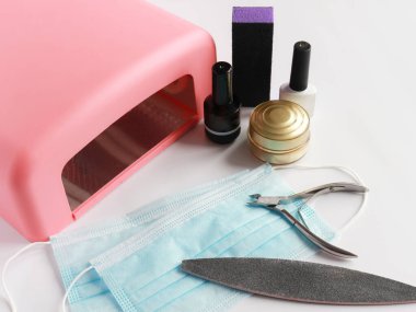 Kıskaç, oje jölesi, vernik kurutmak için lamba ve beyaz arka planda tek kullanımlık sargı.