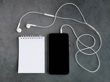 Cep telefonu ve gri bir arka planda kulaklık. Yukarıdan bak. Model