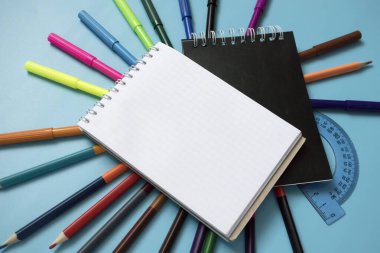 Mavi arka planda renkli kalemler ve işaretler. Mesaj için yer. Okula dönüyorum. Boşluğu kopyala