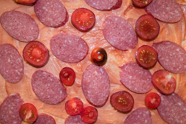 Adım adım talimatlar, dilimlenmiş kiraz domatesleri ve soslu pizza hamurunda dilimler. Adım adım, ev yapımı pizza yapma talimatı. Dördüncü adım. Yukarıdan görüntüle.