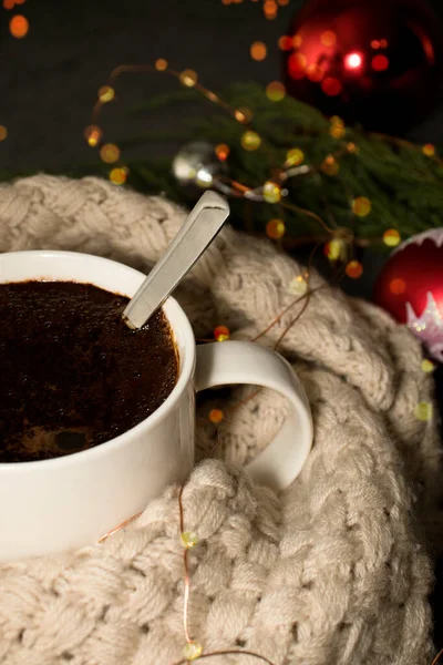 a cup of hot coffee or cocoa in a warm scarf. hot drink in cold weather against the backdrop of Christmas decorations. selective focus.