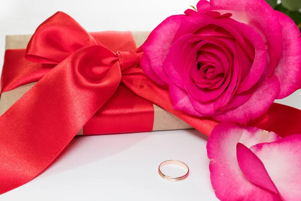Romantic holiday atmosphere. Gift, flowers, ring on a white light background. The concept of a birthday, St. Vantin\'s Day. Selective focus.
