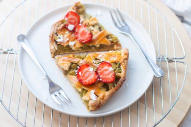 Beyaz tabakta çilek ve kirazlı raventli mevsimlik turta ve beyaz arka plan