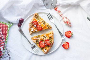 Beyaz tabakta çilek ve kirazlı raventli mevsimlik turta ve beyaz arka plan