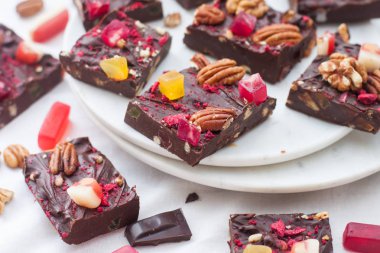 Cevizli çikolata, kurutulmuş ahududu, çilek, çiğnenmiş şeker, lokum ve beyaz tabakta siyah çikolata parçaları..