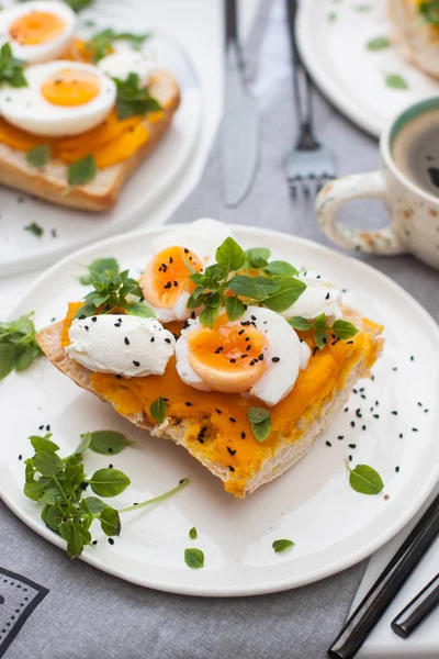 Kabak püresi, haşlanmış yumurta, taze fesleğen ve krem peynirli gri keten kumaş. Arka planda bir fincan kahve.. 