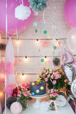 Çikolata toplarıyla süslenmiş doğum günü partisi mavi pastası. Balonlarla, çiçeklerle, gül buketleriyle, sicim lambalarıyla ve kağıt toplarla süslenmiş bir masa.. 