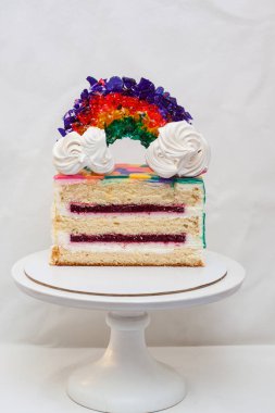 Dilimlenmiş doğum günü vanilyalı pasta ve karamelli gökkuşağı süsü. Düz arkaplan, kopyala.