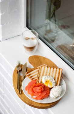 Tostlarla kahvaltı, füme somon, haşlanmış yumurta ve binanın dışında bir fincan kahve. Restoran veya kafe için menü.